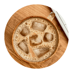 A close-up of a traditional Indian chai tea with spices and tea leaves in a wooden bowl, showcasing authentic flavors from The Indian Pantry.
